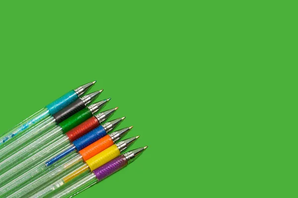 row of colored pens lying on a green background