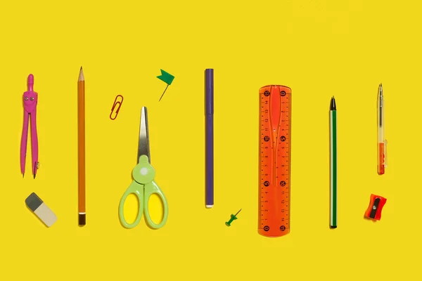 Row of school stationary on a yellow surface — Stock Photo, Image