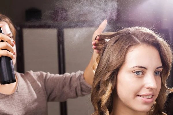 Kuaför saç kıvırcık bir kadının bir saç spreyi ile sabitleme — Stok fotoğraf