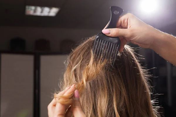 professional haidresser brushing hair of a model close up