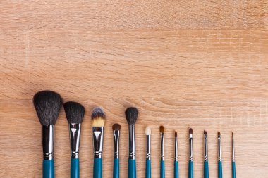 Fırçalar kadar farklı şekiller ve kullanımı olun. ahşap arka plan üzerinde satırda döşeme araçları. Reklam için boş alan