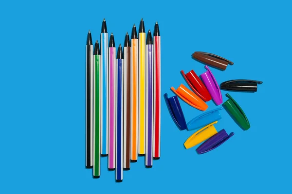 Кольорові ручки лежать на синьому фоні без шапок — стокове фото