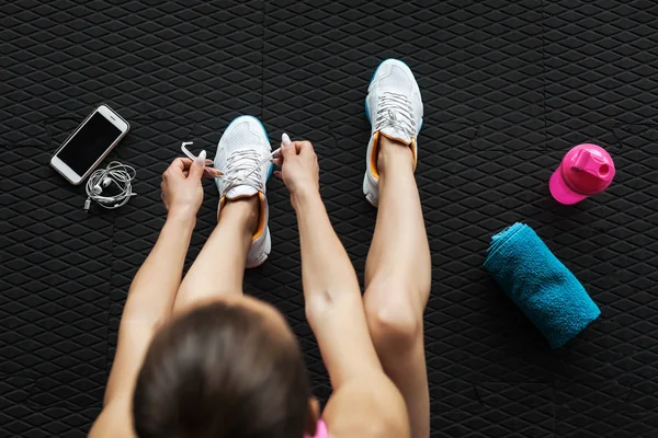 Mujer atando zapatillas en el gimnasio —  Fotos de Stock