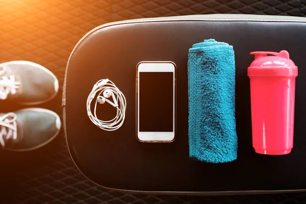 Мобільний телефон, навушники, рушник і шейкер у спортзалі — стокове фото