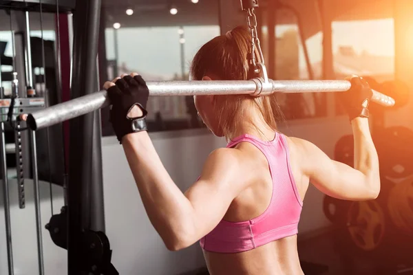 Chica haciendo ejercicio con una barra de pesas en el gimnasio — Foto de Stock