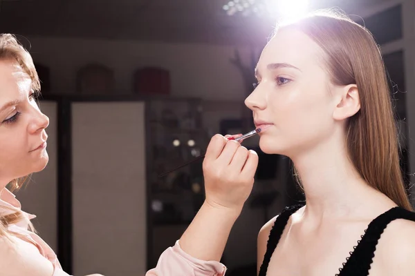 Makeup artist applying a lip gloss on a client — Stock Photo, Image