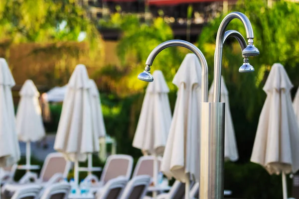 Tumbona, sombrillas y una ducha al aire libre el hotel — Foto de Stock