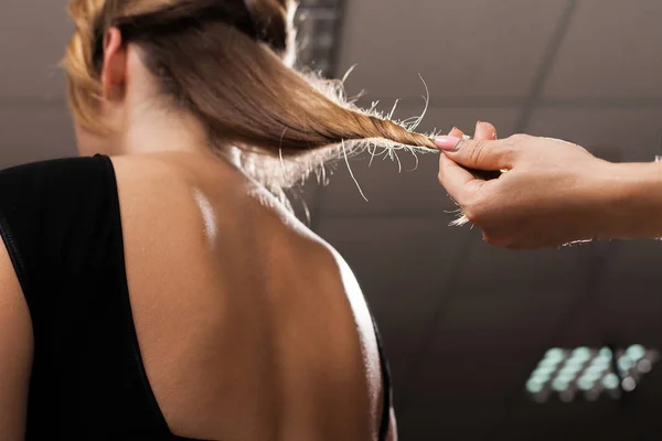 Cabeleireiro segurando o cabelo de um modelo com pontas duplas — Fotografia de Stock