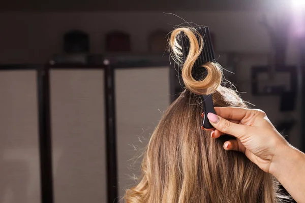 Перукар тримає завиток волосся з гребінцем — стокове фото