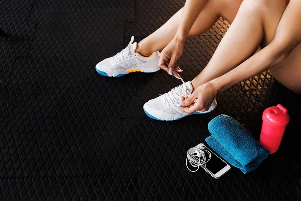 Жінка зав'язує шнурки кросівок у спортзалі — стокове фото