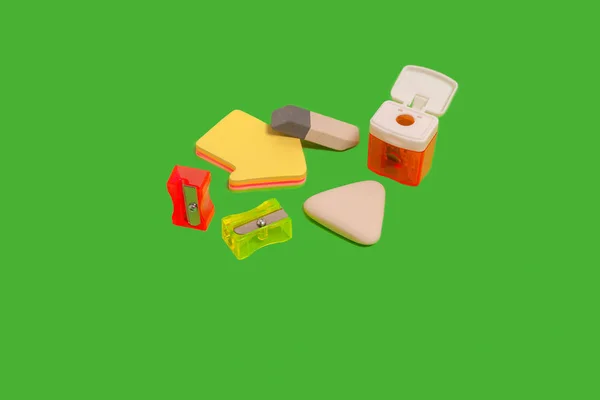 Verschillende gummen en potloodslijpers op een groene ondergrond — Stockfoto