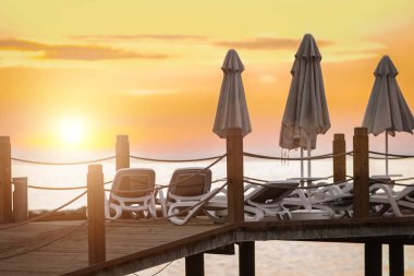 şemsiye ve şezlonglar, iskelede güzel gün batımı