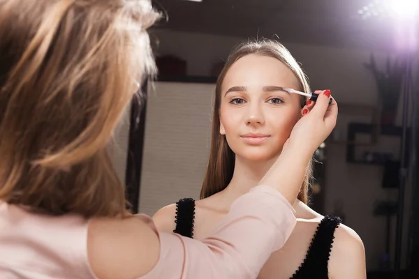Maquillador cepillando las cejas de un cliente — Foto de Stock