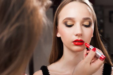 Kırmızı ruj bir kız üzerinde uygulama makyaj sanatçısı