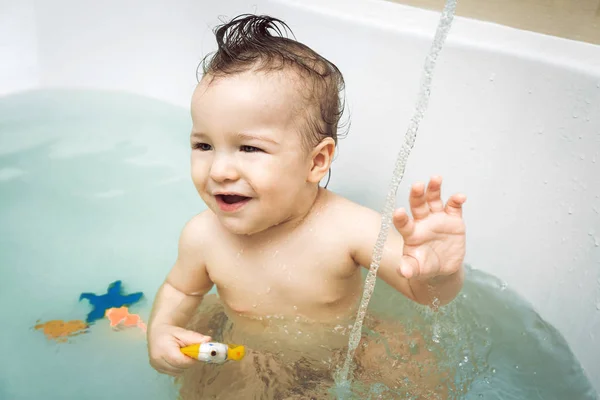 Smiling little baby boy washing in bath Stock Picture