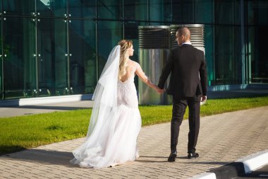 muhteşem gelin ve damat modern binanın yakınında yürüyüş