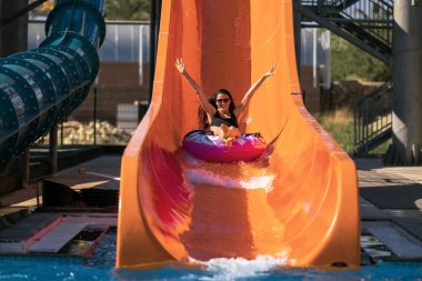 mutlu kadın aqua parkta slayt tarafından aşağı geliyor