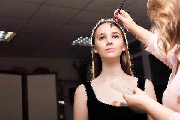 Make-up artiest deppen Foundation op een meisje Stockfoto