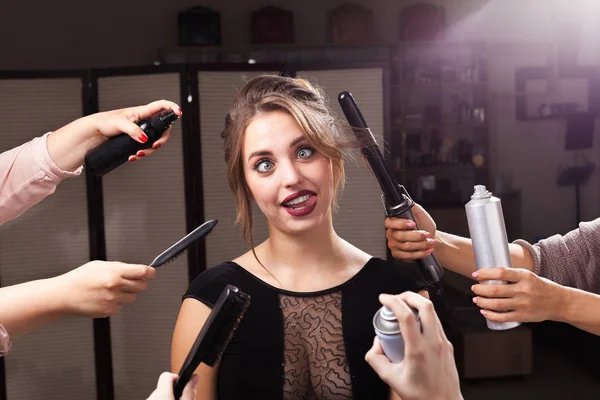 Modelo alegre cercado por mãos com produtos de maquiagem — Fotografia de Stock