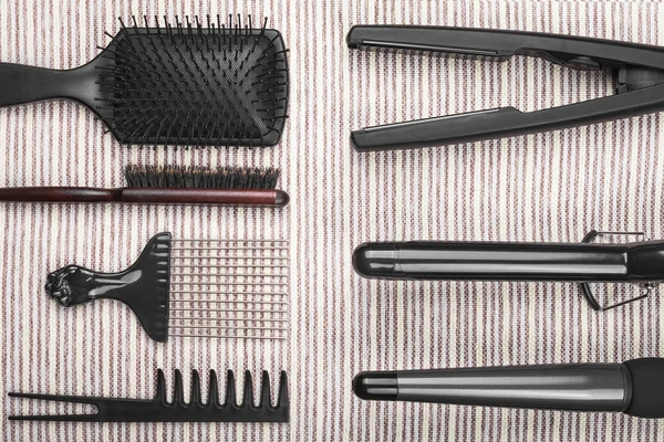 Hair straightening tools lying near various combs — Stock Photo, Image