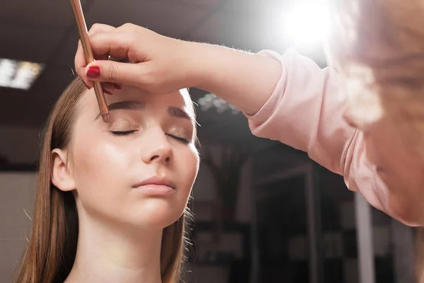 Artista de maquiagem aplicando um primer em uma pálpebra de uma mulher — Fotografia de Stock