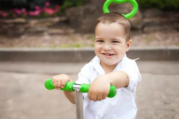 Niño feliz en un triciclo en el parque — Foto de Stock