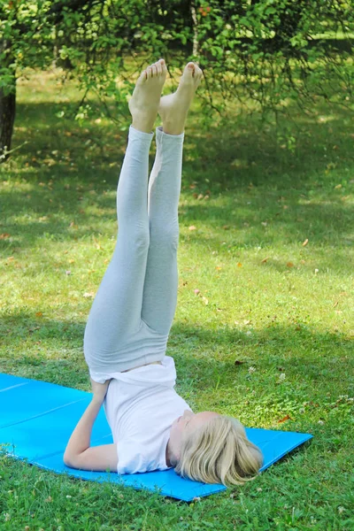 軽装公園でマットの上でヨガの練習で美しいブロンドのプレティーンの女の子 健康的なライフ スタイル アウトドア トレーニング ストック写真