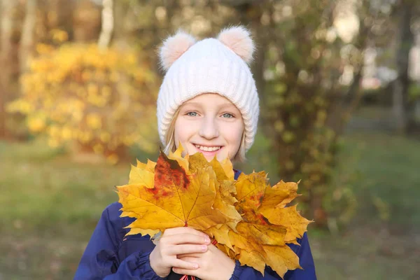 暖かいニット帽子の幸せな笑顔の子供女の子は 黄色の葉の花束を収集します 公園で散歩 — ストック写真