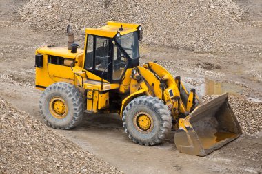 İnşaat malzemeleri deposunda tepelerle çevrili bir buldozer..