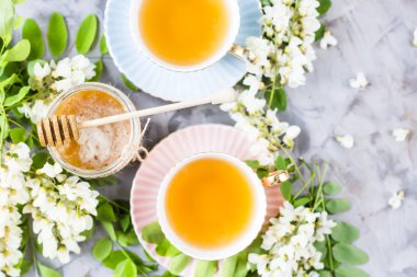 Vintage bardak çay yanında bir kavanoz bal ve akasya gri bir tablo. Doğal tatlandırıcı ballı çayı. Üstten görünüm, düz yatıyordu