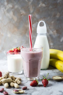 Bir bardak çilek muz smoothie hazırlık için malzemeler arasında. Çilek, muz, süt, yoğurt, chia tohum, susam ve fıstık. Sağlıklı yemek kahvaltı