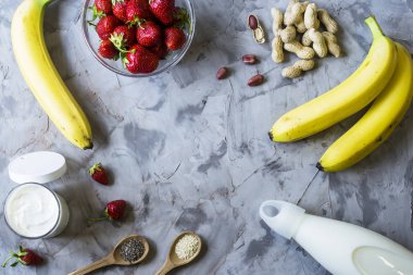 Muz smoothies çilek, üzerinden yemek, süt, yoğurt, chia tohum, susam ve fıstık için malzemeler. Sağlıklı beslenme kahvaltı. Arka plan boşaltmak. Üstten görünüm, düz yatıyordu