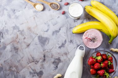 Muz smoothies çilek, üzerinden yemek, süt, yoğurt, chia tohum, susam ve fıstık için malzemeler. Sağlıklı beslenme kahvaltı. Arka plan boşaltmak. Üstten görünüm, düz yatıyordu