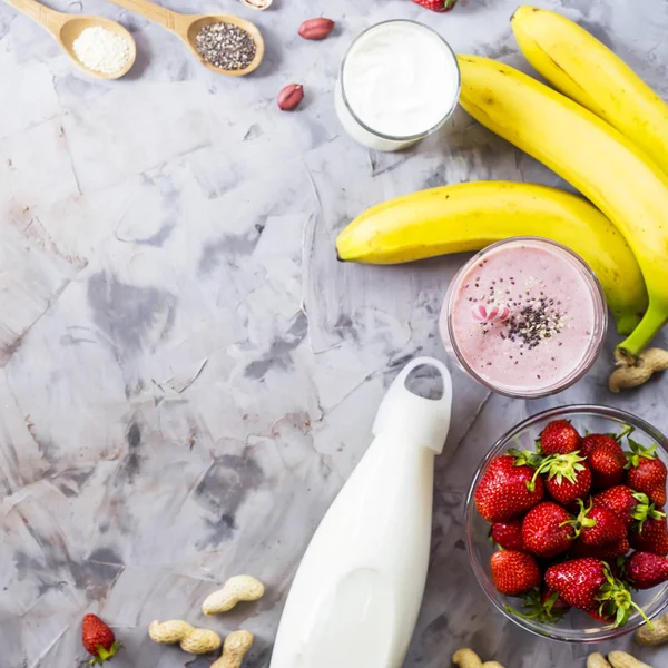 Muz smoothies çilek, üzerinden yemek, süt, yoğurt, chia tohum, susam ve fıstık için malzemeler. Sağlıklı beslenme kahvaltı. Arka plan boşaltmak. Üstten görünüm, düz yatıyordu