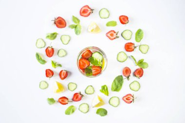 Bir bardak su çilek, salatalık, nane ve limon ilavesi ile. Parlak malzemelerin beyaz bir arka plan üzerine bir daire içinde. Detoks ve spor kavram. Üstten görünüm, düz yatıyordu