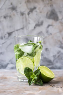 Bir bardak mojito buz, nane ve limon bir cam gri bir tablo. Yaz alkolsüz içecek konsepti