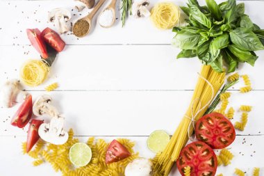 Pişirme - yemek makarna, fesleğen, sebze, kireç ve bir daire şeklinde bir beyaz tahta masada baharat. Üstten görünüm, düz yatıyordu, boşaltmak