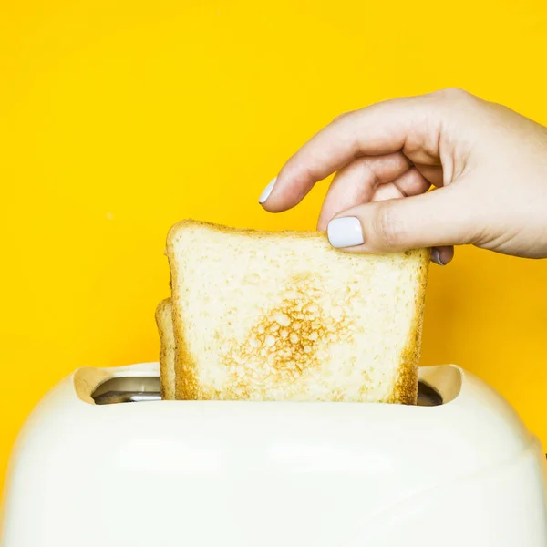 Pan Tostado Sobresale Tostadora Sobre Fondo Amarillo Mano Una Mujer — Foto de Stock