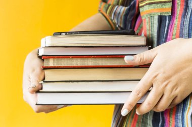 Çizgili gömlekli bir kız öğrencinin ders kitapları bir yığın onun elinde tutuyor. Üniversite eğitimi için hazırlanıyor. Geri okul kavramı