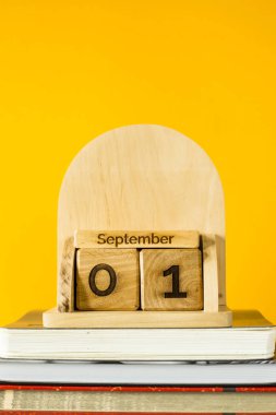 1 Eylül sarı bir arka plan üzerinde çalışmaya ders kitapları arasında ahşap bir takvim. Geri okul kavramı