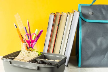 Beslenme çantası gıda - sandviç, fındık ve çilek ile bir yığın kitap ve kalem ve kurşun kalem ile bir bardak yanında duruyor. Çalışma sırasında sofra
