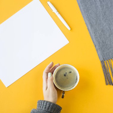 Yukarı alay - beyaz kağıt yanında bir fincan kahve el ve sonbahar bir eşarp. Üstten görünüm, düz yatıyordu