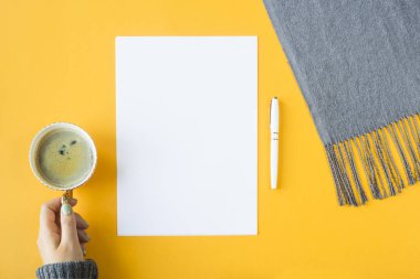 Yukarı alay - beyaz kağıt yanında bir fincan kahve el ve sonbahar bir eşarp. Üstten görünüm, düz yatıyordu