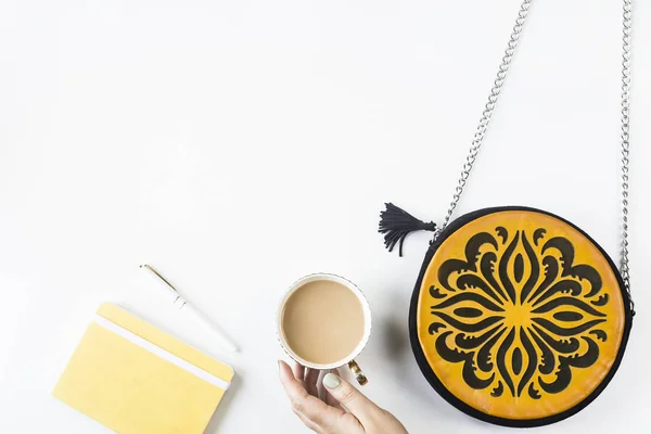 女性アクセサリー明るいオレンジ バッグ黄色日記 ペンと白い背景の上にコーヒー カップの横に黒の飾り付き フラット トップ ビュー レイアウト コピー スペース — ストック写真
