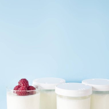 Ev yapımı yoğurt kavanoz ahududu üzerinde mavi bir arka plan ile. Kopya alanı