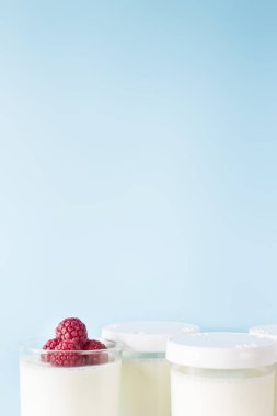 Ev yapımı yoğurt kavanoz ahududu üzerinde mavi bir arka plan ile. Kopya alanı