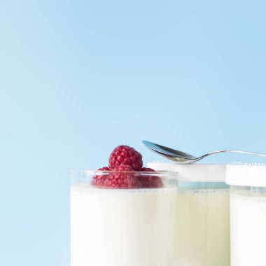 Ev yapımı yoğurt kavanoz ahududu üzerinde mavi bir arka plan ile. Kopya alanı