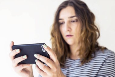 Kız bir akıllı telefon tutarak ve ekrana bakarak. Mobil Oyunlar. Teknoloji ve online hayat