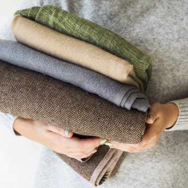 Ekoseler ve eşarp gri süveterli kadın elinde yığını. Hazırlık soğuk sonbahar ve kış. Mevsimlik dolap kavramı