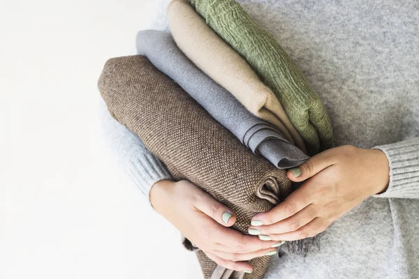 一个穿灰色毛衣的女人手中的一叠格子和围巾 在寒冷的秋天和冬天准备 季节性衣柜概念 — 图库照片